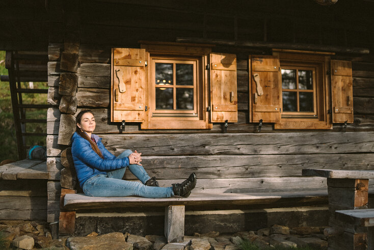 Frau entspannt vor Almhütte | © Daniel Gollner