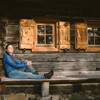 Frau entspannt vor Almhütte | © Daniel Gollner